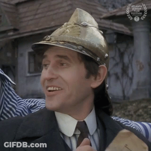 A Man Wearing A Fireman 'S Helmet Is Smiling In Front Of An Atlanta International Film Festival Sign GIF