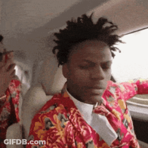 A Man Wearing A Floral Shirt And Tie Is Sitting In A Car GIF