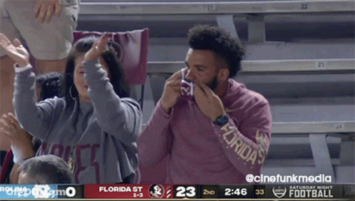 A Man Wearing A Florida Sweatshirt Wipes His Nose During A Football Game GIF