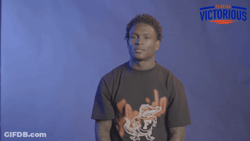 A Man Wearing A Florida Victorious Shirt Holds His Hands Up GIF