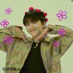 A Man Wearing A Flower Crown Is Making A Heart With His Hands . GIF