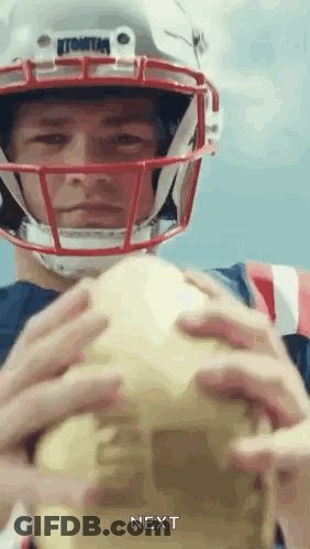 A Man Wearing A Football Helmet Is Holding A Football In His Hands And Says Next . GIF