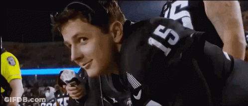 A Man Wearing A Football Jersey With The Number 15 On It Is Smiling . GIF