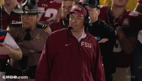 A Man Wearing A Fsu Jacket Is Standing In Front Of A Crowd . GIF