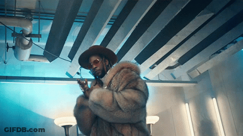 A Man Wearing A Fur Coat And A Hat Holds A Gun GIF
