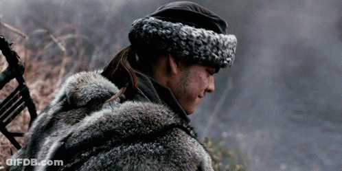 A Man Wearing A Fur Coat And A Hat Is Standing In A Field . GIF