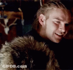A Man Wearing A Fur Coat Is Smiling In Front Of A Deer Skull GIF