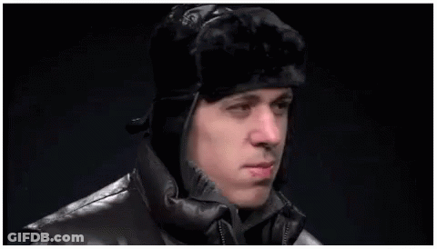 A Man Wearing A Fur Hat And A Leather Jacket Is Making A Funny Face . GIF
