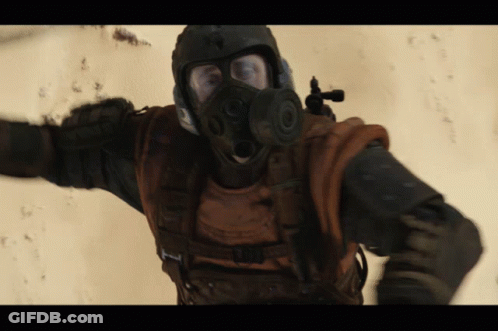 A Man Wearing A Gas Mask And A Helmet With A Gun GIF