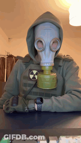 A Man Wearing A Gas Mask And A Hoodie Has A Watch On His Wrist That Shows The Time As 8:30 GIF