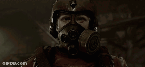 A Man Wearing A Gas Mask And Helmet Looks At The Camera GIF