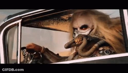 A Man Wearing A Gas Mask Is Driving A Car In The Desert . GIF