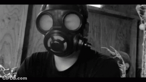 A Man Wearing A Gas Mask Is Looking At The Camera GIF