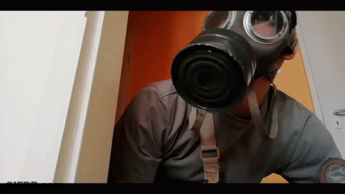 A Man Wearing A Gas Mask Is Looking Out A Door GIF
