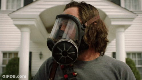 A Man Wearing A Gas Mask Is Standing In Front Of A House GIF