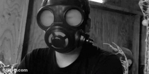 A Man Wearing A Gas Mask Looks At The Camera In A Black And White Photo GIF