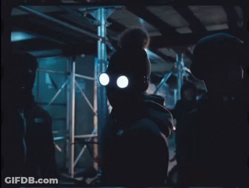 A Man Wearing A Gas Mask Stands In A Dark Room With Chinese Writing On The Bottom Right GIF