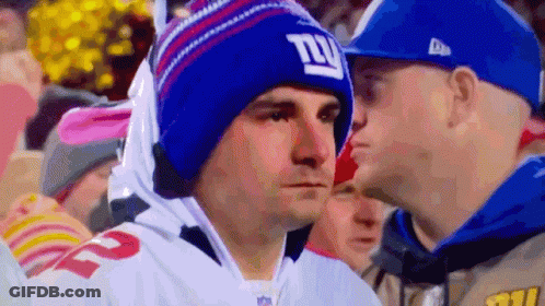 A Man Wearing A Giants Hat Looks At Another Man In A Blue Hat GIF