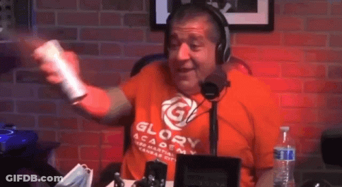 A Man Wearing A Glory Academy Shirt Is Holding A Remote Control In Front Of A Microphone . GIF