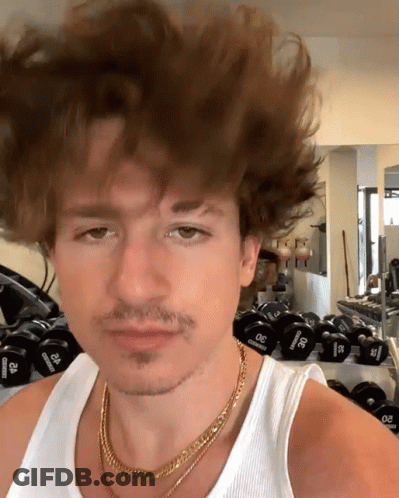 A Man Wearing A Gold Chain And A White Tank Top Stands In Front Of A Row Of Dumbbells That Say 30 Pounds GIF