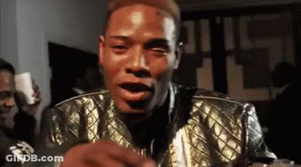 A Man Wearing A Gold Jacket Is Making A Funny Face . GIF