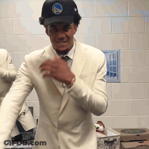 A Man Wearing A Golden State Warriors Hat And White Suit GIF