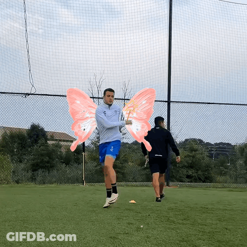 A Man Wearing A Gray Jacket And Blue Shorts Has Pink Wings On His Arms GIF