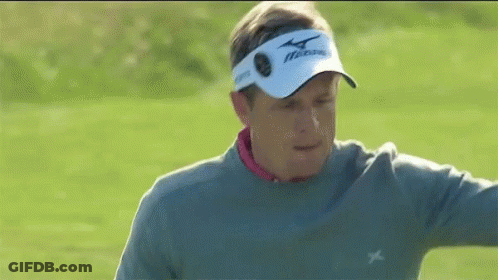 A Man Wearing A Gray Sweater And A White Hat Is Standing On A Golf Course . GIF