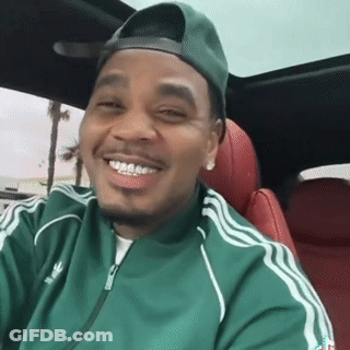 A Man Wearing A Green Adidas Jacket And A Green Hat Is Smiling While Sitting In A Car . GIF
