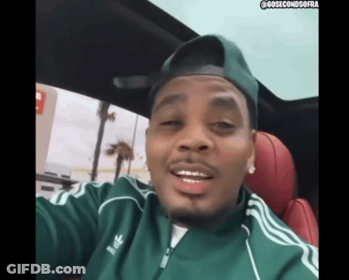 A Man Wearing A Green Adidas Jacket And A Hat GIF