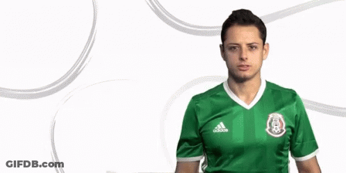 A Man Wearing A Green Adidas Jersey Is Standing In Front Of A White Background GIF