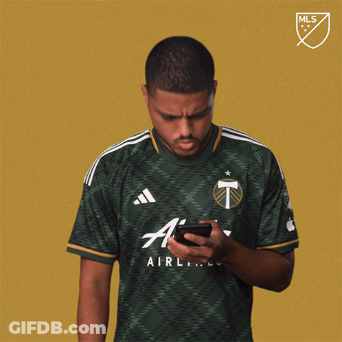 A Man Wearing A Green Airlines Jersey Looks At His Phone GIF