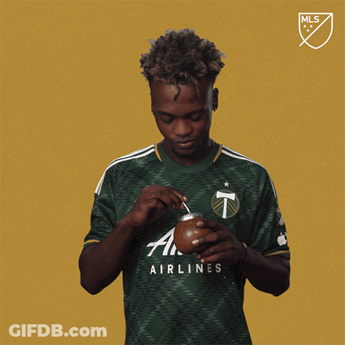 A Man Wearing A Green Airlines Shirt Holds A Cup GIF