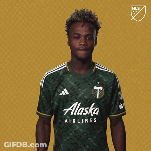A Man Wearing A Green Alaska Airlines Shirt Holds Up A Yellow Card GIF