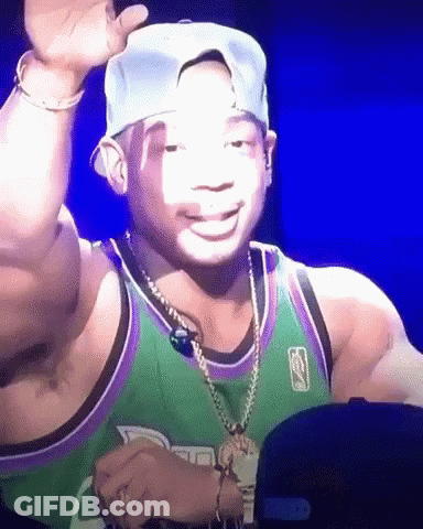 A Man Wearing A Green And Purple Jersey And A Hat Is Smiling GIF