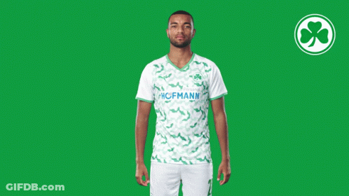 A Man Wearing A Green And White Hofmann Jersey Stands In Front Of A Green Background GIF
