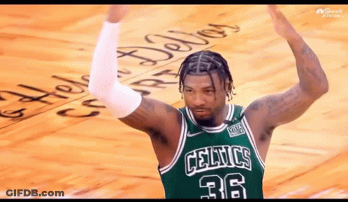 A Man Wearing A Green Celtics Jersey Is Standing On A Court With His Arms In The Air . GIF