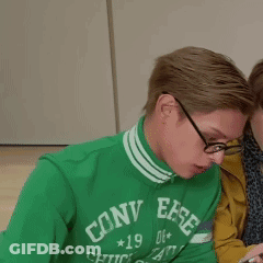 A Man Wearing A Green Converse Sweatshirt Looks At His Phone GIF