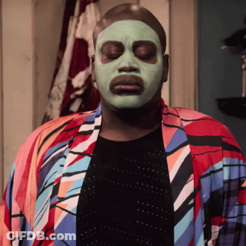 A Man Wearing A Green Face Mask And A Colorful Robe GIF