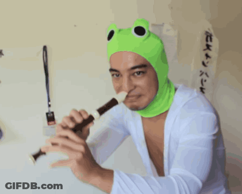 A Man Wearing A Green Frog Hat Is Holding A Flute GIF