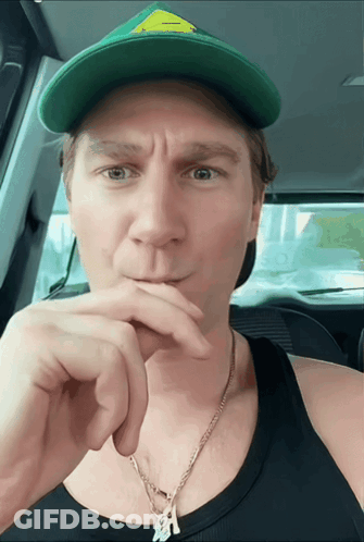 A Man Wearing A Green Hat With A Yellow Triangle On It GIF