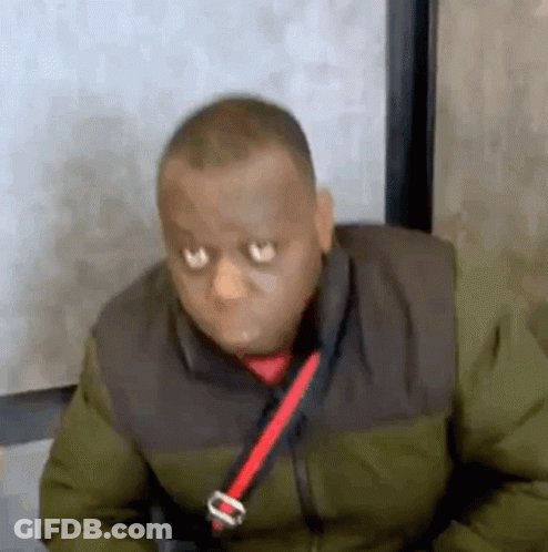 A Man Wearing A Green Jacket And A Red Tie Is Sitting In A Chair . GIF