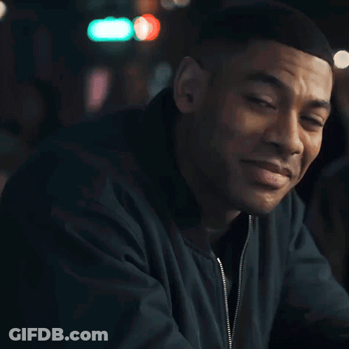 A Man Wearing A Green Jacket Is Smiling And Looking At The Camera GIF