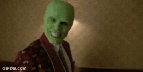 A Man Wearing A Green Mask Is Sitting On A Bed In A Room . GIF