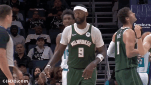 A Man Wearing A Green Milwaukee Jersey Stands In Front Of A Referee GIF