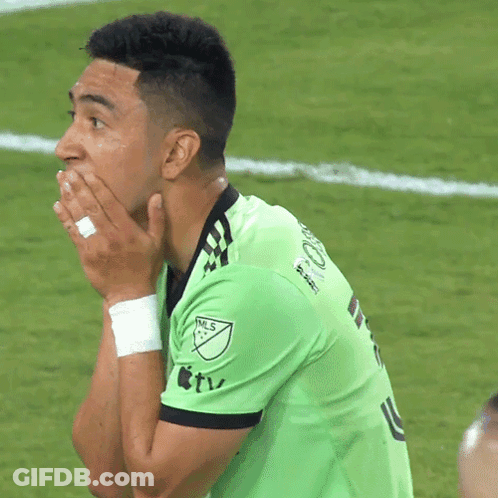 A Man Wearing A Green Nls Jersey Covering His Mouth With His Hands GIF