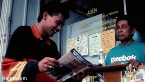 A Man Wearing A Green Reebok Shirt Stands In Front Of A Window GIF