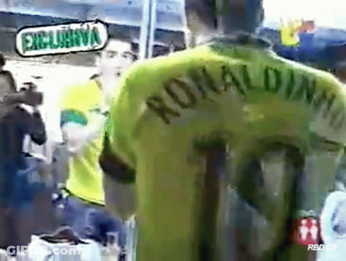 A Man Wearing A Green Ronaldinho Jersey Stands In Front Of A Camera GIF