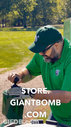A Man Wearing A Green Shirt And A Green Hat Is Working On A Giant Bomb GIF