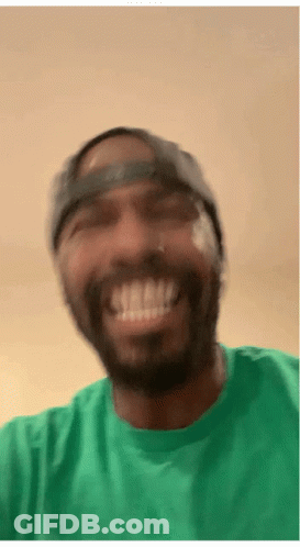 A Man Wearing A Green Shirt And A Hat Smiles GIF